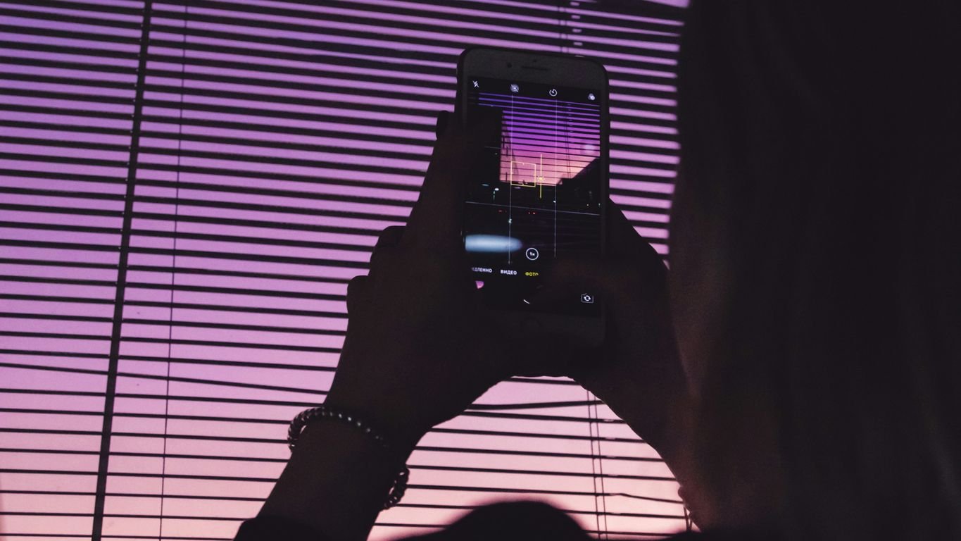 person taking picture of the purple sky using a smartphone